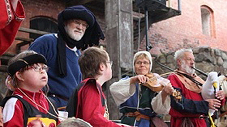 Pedagoger och barn i medeltidskläder spelar och sjunger.