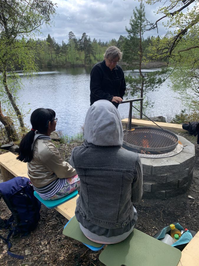 Två elever sitter vid en grill med utsikt över sjön.