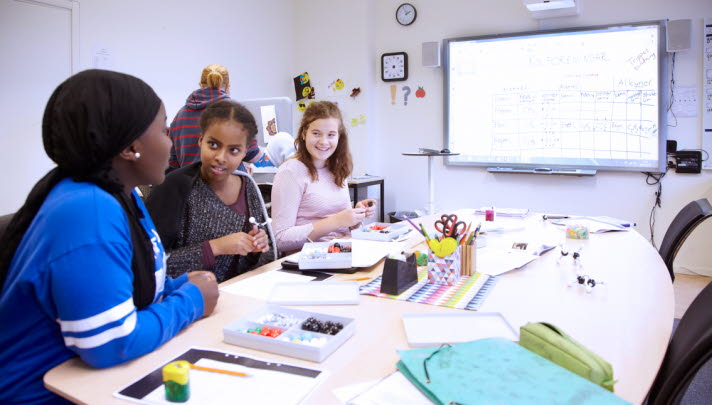 Bilden visar tre elever som sitter i en konferenssal.