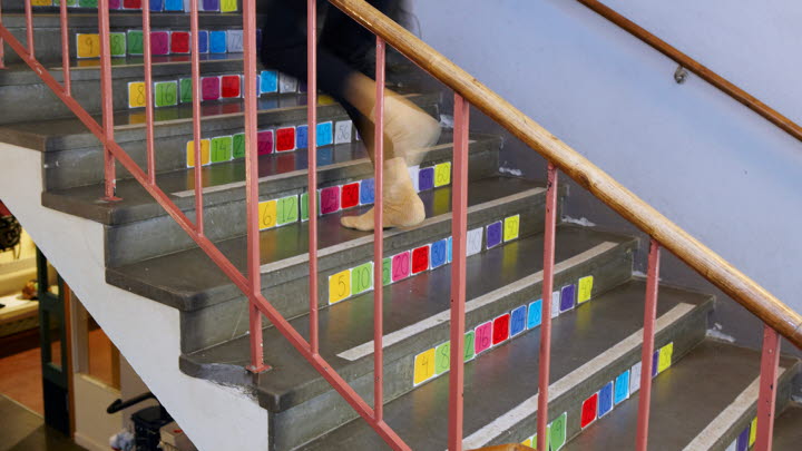 Någon springer uppför en trappa med färgmarkeringar på varje trappsteg.