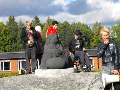 Students outdoors next to a tactile statue lookin like a dragon.