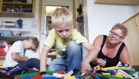 Två barn och en lärare som leker med lego