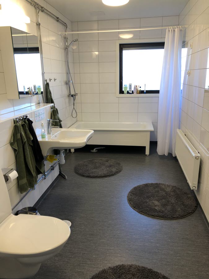 Toalettstol, tvättställ och badkar med duschdraperi.