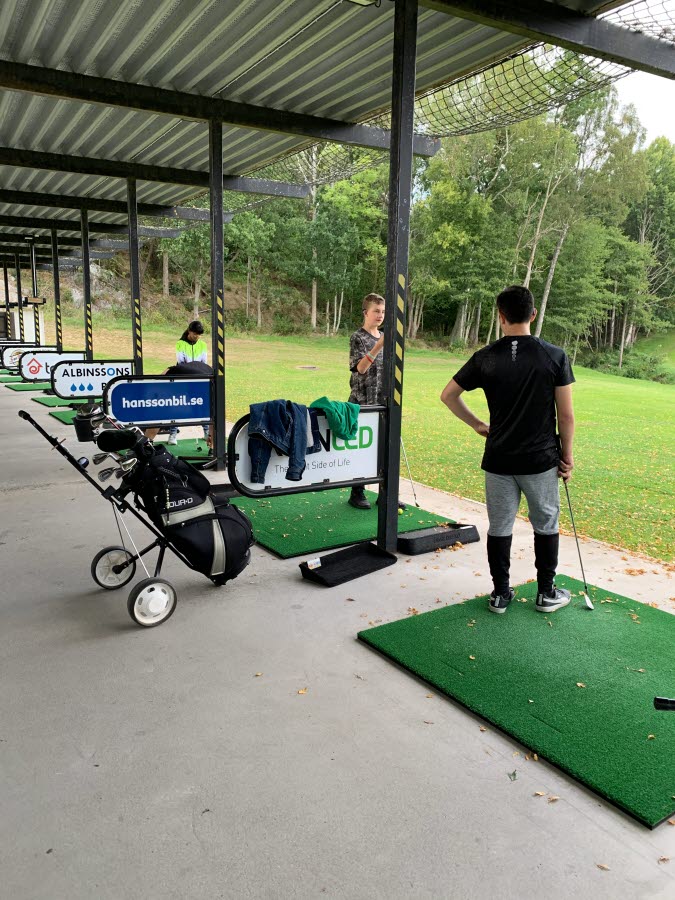 Två elever står och spelar golf.