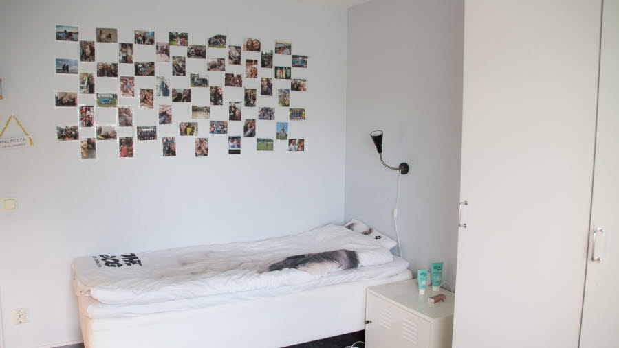 Sovrum med säng, garderob och foton på väggen.