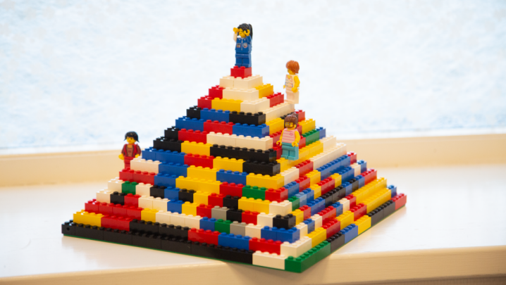 En pyramid byggd av lego i olika färger, på olika ställen i den står legofigurer