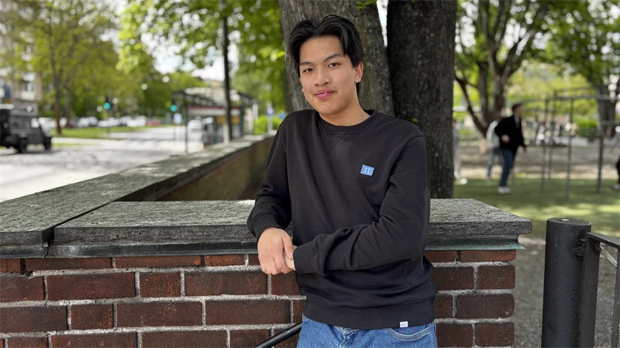 Sean står framför en tegelmur.