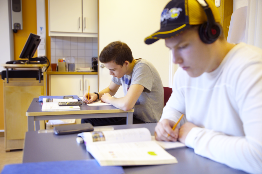 Två elever vid varsin skolbänk som skriver