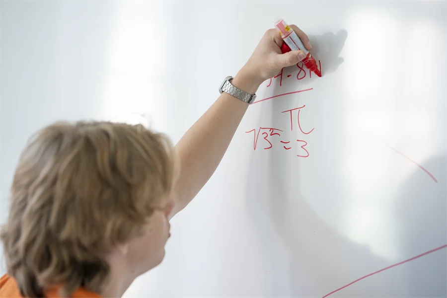 Elev skriver ett matteal på en vit tavla.
