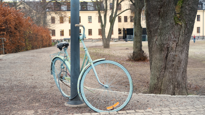 En gammal cykel som står lutad mot en lyktstolpe.