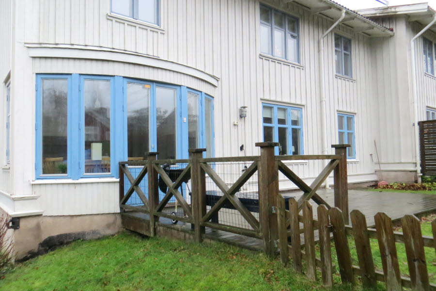Baksidan av ett vitt hus med blå fönsterkarmar.