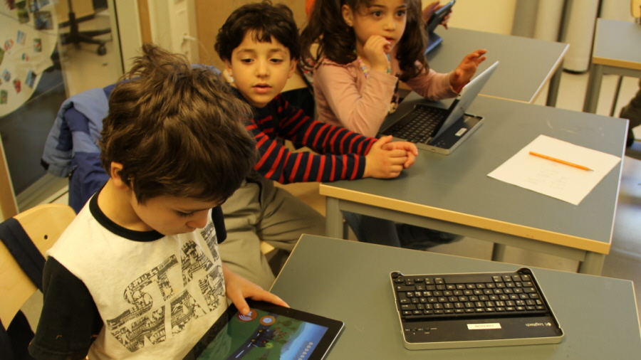 Två elever spelar ett pedagogiskt spel på en stor bildskärm