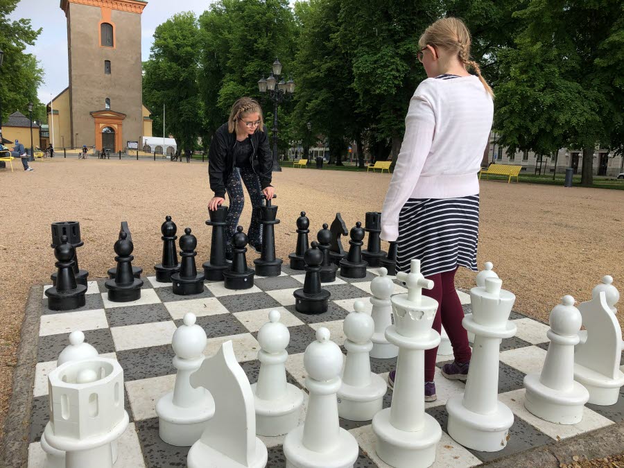 Två elever står på varsin del av schackbrädan utomhus.
