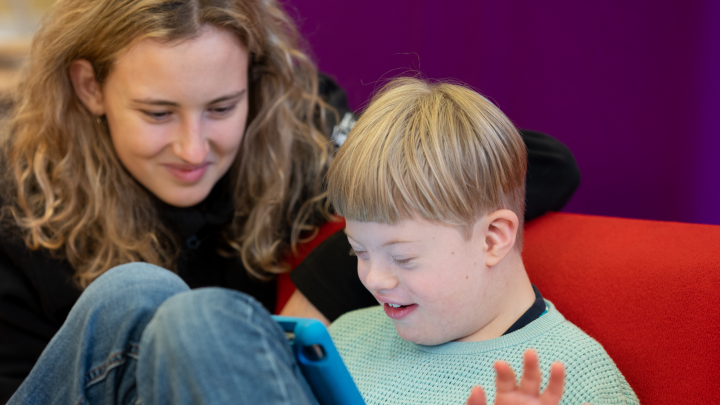 Ett barn och en vuxen person tittar på en surfplatta tillsammans.