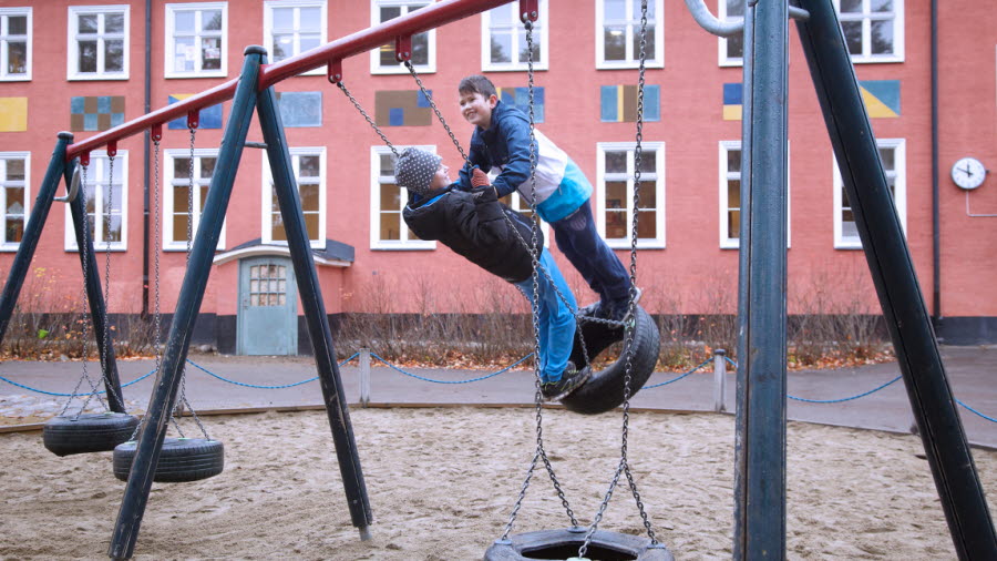 Bilden visar två elever som gungar tillsammans på en lekplats.