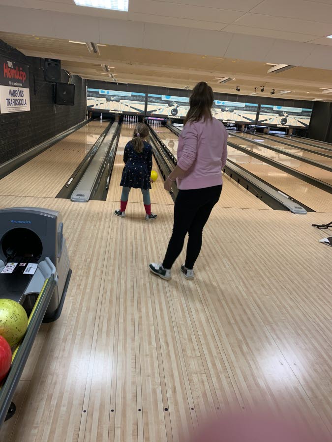 En elev skjuter in en bowlingklot och en personal finns bakom som stöd.