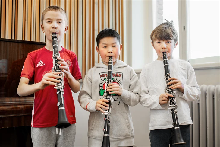 Tre elever spelar blåsinstrument tillsammans.
