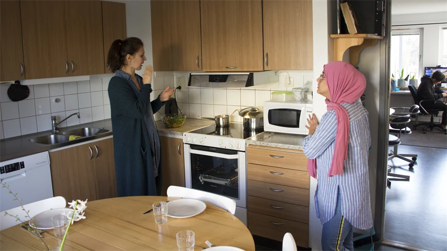 Två personer i ett kök. Ett dukat bord.