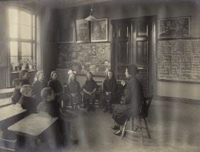 En kvinnlig lärare sitter och undervisar en grupp elever