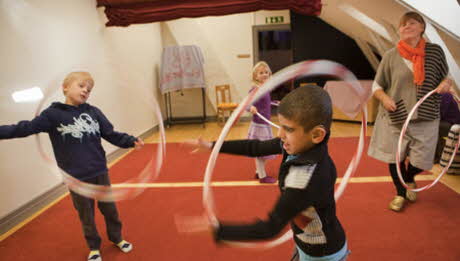 Yngre elever och en pedagog gör övningar med rockringar
