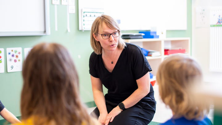 Bilden visar lärare som sitter på en bänk och undervisar elever.