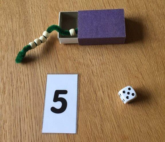 Siffran 5, en tärning som visar fem, och ett snöre med fem pärlor