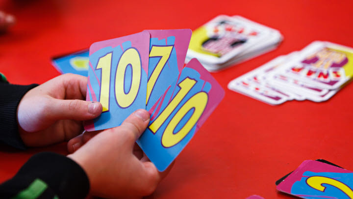 Bild på två händer som håller i flera kort med nummer på.
