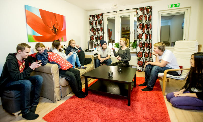 Ett gäng ungdomar umgås i ett rum med soffor och bord