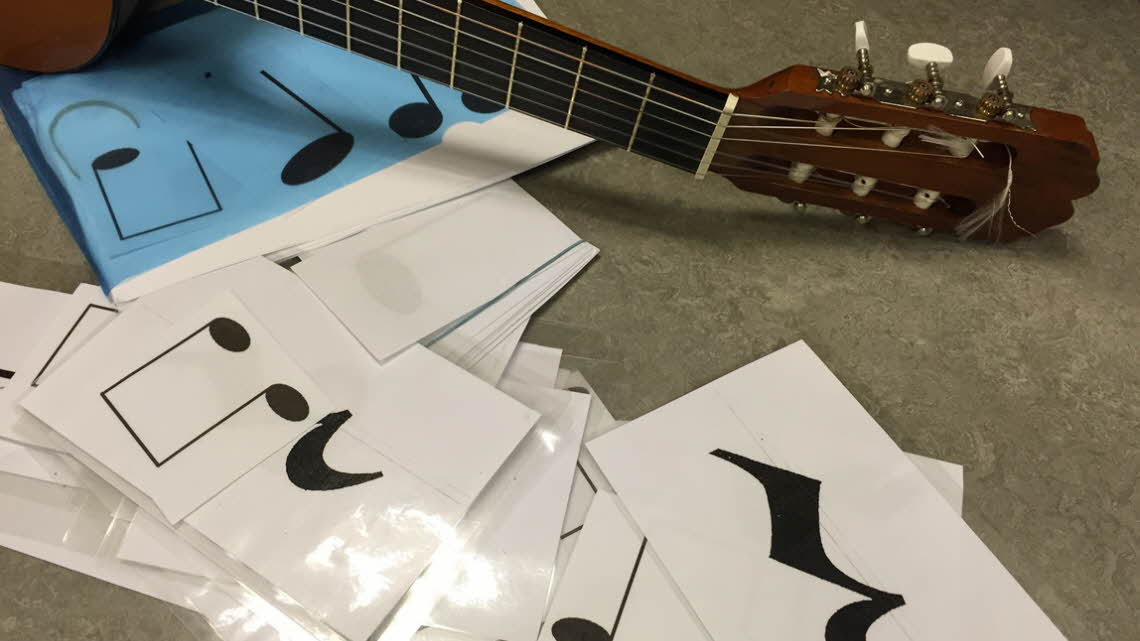 Kort med noter bredvid en gitarr