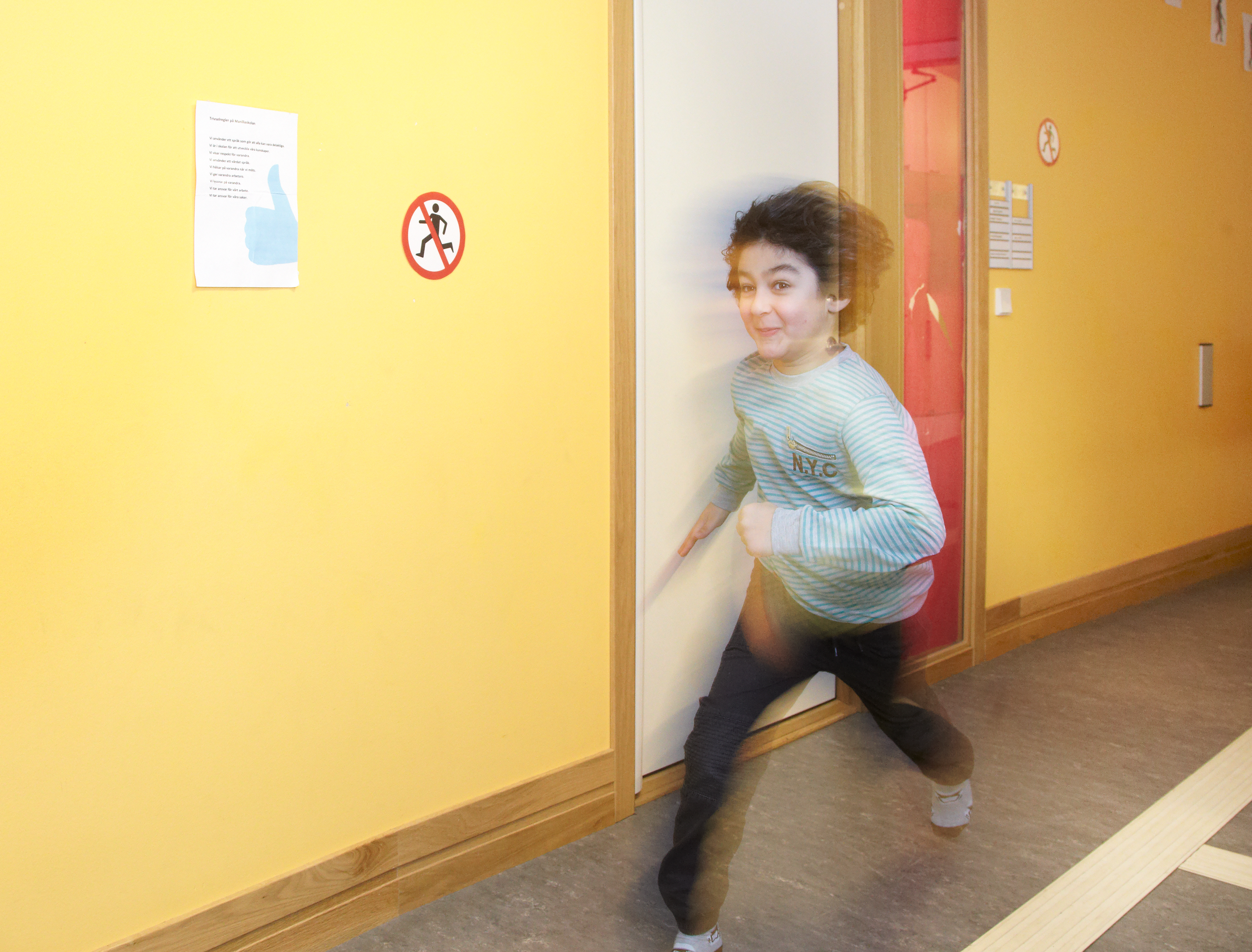 Bilden visar ett barn som springer i korridoren.